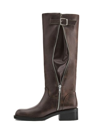 Botte haute en cuir marron foncé avec une fermeture éclair latérale partiellement ouverte et une sangle décorative à boucle près du haut.