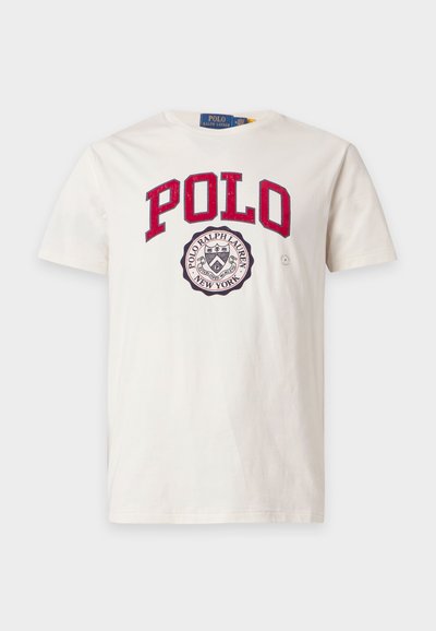Λευκό κοντομάνικο T-shirt με κόκκινο κείμενο "POLO" και στρογγυλό λογότυπο Polo Ralph Lauren New York σε ασπρόμαυρο στο στήθος.