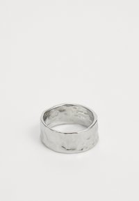 Sølvring med hamret tekstur, bred ringkant og glatt innside. Reflekterende overflate fremhever den uregelmessige utformingen.