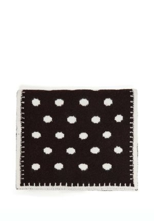 Couverture rectangulaire en tricot noire avec des pois blancs espacés uniformément et une bordure blanche cousue sur un fond blanc.