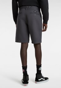 Grau Shorts aus leichtem Material, ausgestattet mit zwei Gesäßtaschen mit Knopfverschlüssen und einem Markenetikett am Bund.