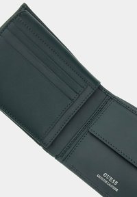 Green genuine leather wallet with multiple card slots, a coin compartment, and embossed "GUESS" logo. Smooth texture and neat stitching details.