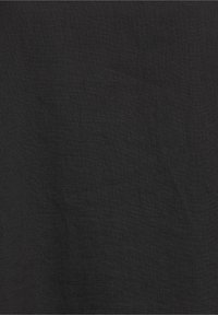 Tissu noir texturé avec un motif tissé subtil, des plis visibles et une finition mate douce.