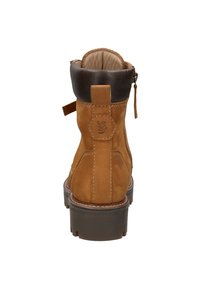 Braune Wildleder-Ankle Boots mit einem schwarzen Lederkragen, einem Reißverschluss hinten, einem Logo, das auf der Ferse eingeprägt ist, und einer dickeren Gummisohle. Schlichte Nähedetails.