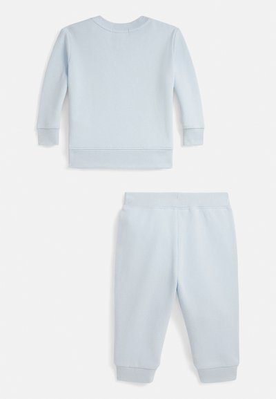 Gaiši zils džemperu un sporta bikses komplekts, izgatavots no mīksta auduma. Ar ribveida aprocēm un apakšmalu, vienkāršs dizains bez rakstiem.