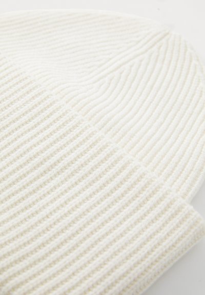 Cream-colored beanie with a textured ribbed pattern, featuring a snug fit and soft, knitted fabric. Ideal for warmth in cooler weather.