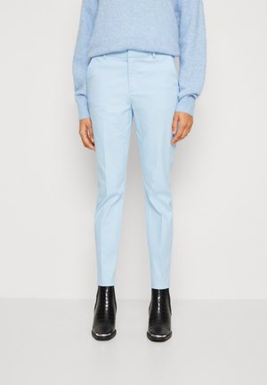 Lyseblå slim-fit bukser kombineret med en matchende lyseblå sweater og sorte teksturerede ankelstøvler.
