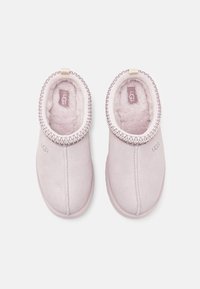 Rosa mockakängor utan snörning med en fluffig inredning, prydda med en vävd kant runt vristen och en subtil logotyp på sidan.