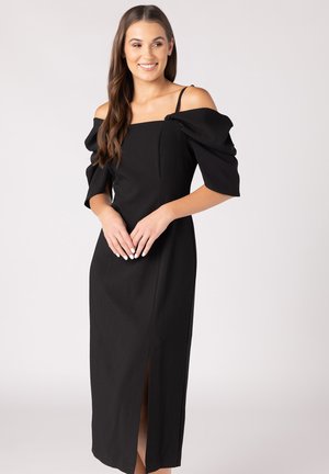 Abito nero off-shoulder con maniche a palloncino, corpino aderente e spacco laterale. Realizzato in tessuto morbido, presenta un collo quadrato e spalline regolabili.