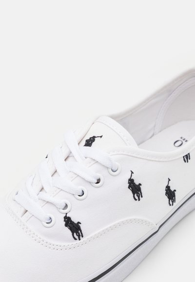 Tenis de lona brancos com logótipos de jogador de polo bordados a preto, biqueira redonda, design de atacadores e acabamento da sola de borracha preta.