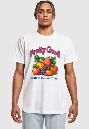 Hvid t-shirt med et farverigt pixelkunst frugt design med appelsiner, pærer og druer. Teksten lyder "Fruity Good" og inkluderer "© 1990 Vitamin C Inc."