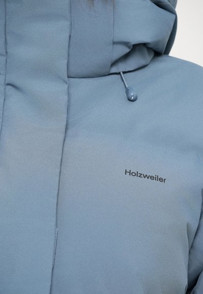 Light blue insulated jacket featuring a high neck, drawstring hood, and black "Holzweiler" logo on the front. Smooth, soft texture.