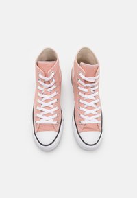 Zapatillas altas de lona en rosa claro con cordones blancos, puntera reforzada y suela de goma negra. Textura suave, branding mínimo.