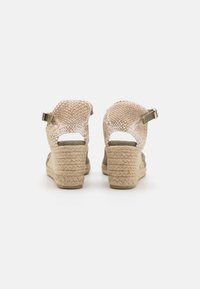 Kile sandaler med et vevet beige stoffoverdel og en naturlig jute såle. Har justerbare stropper og åpen hældesign for pusteevne.