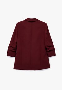 Bordeaux frakke med skræddersyet design, der har krave, tætsiddende ærmer og to forlommer. Glat tekstur med rene linjer.