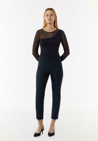 Marineblauw body met doorzichtige, gestreepte mouwen; gecombineerd met op maat gemaakte donkere broeken en zwarte hakken. Minimalistisch ontwerp met strakke lijnen.
