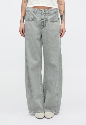 Grå vidbente dongeribukser med høy midje, knappelukking og sydd detaljering på lommer og sømmer. Jevn tekstur, uformelt design.