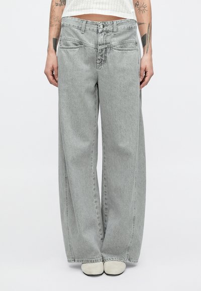 Jeans en denim gris à jambes larges avec une taille haute, fermeture bouton, et des détails cousus sur les poches et les coutures. Texture lisse, design décontracté.