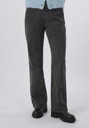 Fekete egyenes szárú kordnadrág fekete vastag csizmával és világoskék bolyhos kardigánnal viselve.