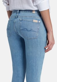 Jeans azzurri chiari con vestibilità slim, dotati di tasche posteriori e un motivo a onda cucito. Realizzati in denim con una finitura morbida e strutturata.
