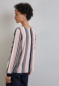 Top a maniche lunghe a righe con righe verticali in rosa, bordeaux e nero. Il dettaglio sul retro presenta un accento nero a contrasto.