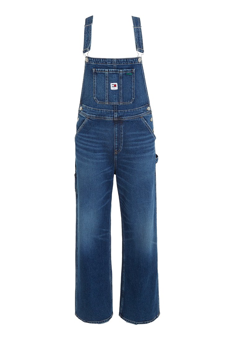 Salopette en denim bleu avec bretelles réglables, jambes larges, poche avant et quincaillerie en métal. Présente un délavage décoloré et une coupe décontractée.