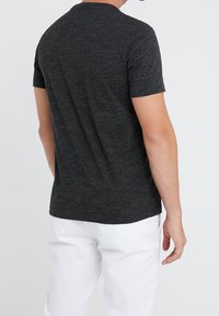 Mörkgrå kortärmad T-shirt i mjukt, texturerat tyg med en slät yta. Har en rund halsringning och en avslappnad passform bak.