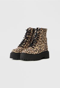 Leopardskinds mønstrede combat støvler lavet af stof, med sorte snørebånd, en tyk platåsål og en lynlåsdetalje på siden.