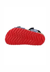 Sandalia infantil con suela de goma roja que presenta un patrón de zigzag, parte superior azul con diseño de camuflaje y correas ajustables negras.