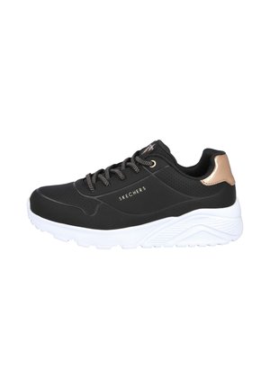 Zapatilla negra de Skechers con suela blanca, acento en el talón en bronce y cordones negros, vista lateral que muestra detalles perforados y el logotipo.