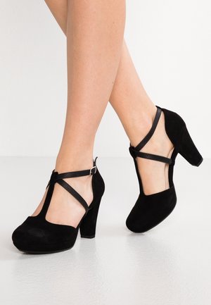 Chaussures à talons hauts en daim noir avec un design à bride en T, boucle à la cheville et bout rond. Brides texturées et talon block solide.