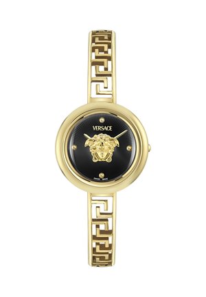 Złoty zegarek Versace na nadgarstek z czarną tarczą, emblematem głowy Meduzy na środku, złotą bransoletą z greckim wzorem klucza oraz minimalistycznymi znacznikami godzin.