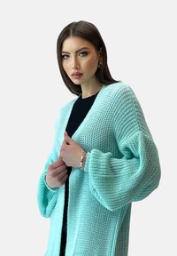 Cardigan lavorato a maglia blu chiaro con maniche oversize e una vestibilità morbida, caratterizzato da un motivo testurizzato e un design aperto sul davanti.