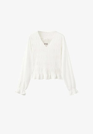 Bijela bluza s dugim rukavima i V-izrezom, teksture nabrane tkanine, skupljenih manžeta i naboranog ruba. Ima vezanje na izrezu.
