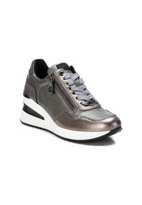 Zapatilla metálica gris con suela en cuña, acentos texturizados y cierre lateral. Presenta cordones grises y una suela de goma en blanco y negro.