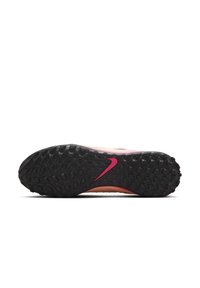 Nike soccer shoe outsole featuring a textured black rubber sole with a pink swoosh logo and a dynamic pattern for traction.