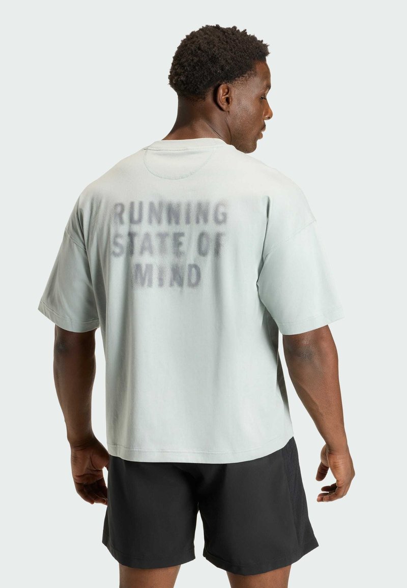 Lichtgroen oversized T-shirt met korte mouwen, met de tekst "RUNNING STATE OF MIND" in donkere spuitverf op de achterkant.