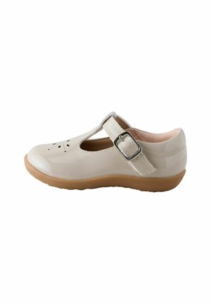 Blank beige Mary Jane-sko med spænde, perforeret design på tåen og beige gummi sål, set fra siden.