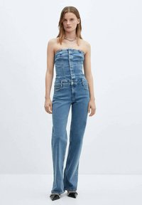 Denim jumpsuit med strapless design, lyseblå farve og en tætsiddende talje. Har flared ben og frontknaplukning. Tekstureret stof.
