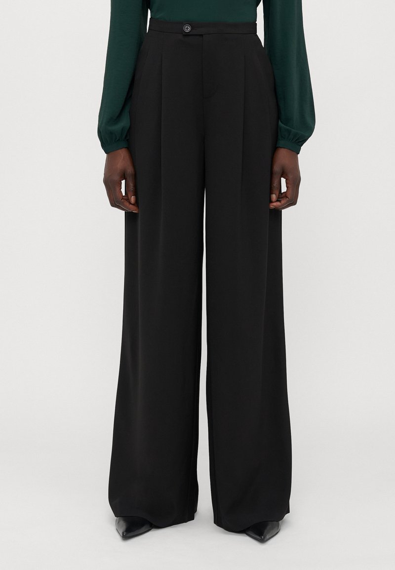 Zwarte, high-waisted wijde broek met plooien aan de voorkant, een enkele knoopsluiting en een gladde, gestructureerde stof.