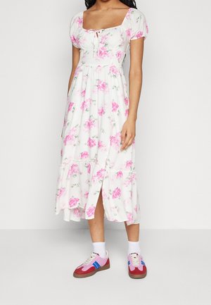 Bloemenjurk met korte pofmouwen, vierkante halslijn, witte basis, roze rozen, geniveauerde zoom en zijschuif, gecombineerd met kleurrijke sneakers.