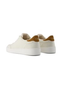 Vita kanvas sneakers med en texturerad finish, en slät vit gummisula och en tan läderdetalj vid hälen med logotyp.