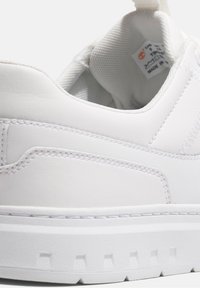 Sneaker bianca in pelle con finitura testurizzata, cuciture rinforzate e una robusta suola in gomma bianca con un design del battistrada a motivi.