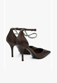 Brown satin high-heeled shoes with a pointed toe, ankle strap featuring clear rhinestones, and a tapered stiletto heel.