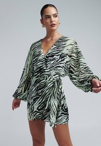 Groene en zwarte zebra-print wikkeljurk met lange, flowy mouwen en een diepe V-hals, gemaakt van lichtgewicht, doorschijnende stof.