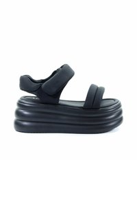 Czarne sandały na platformie mają grubą, zaokrągloną podeszwę, szerokie paski oraz regulowany pasek na kostkę, wykonane z gładkiego materiału syntetycznego.