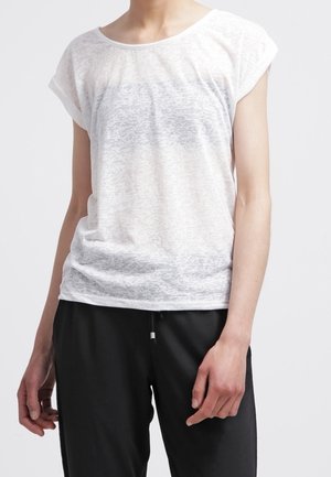 Hvid, let T-shirt med rullede ærmer, der har et subtilt teksturmønster og en afslappet pasform, parret med sorte bukser.