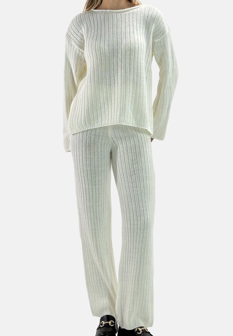 Ensemble pull et pantalon en maille côtelée blanche ; coupe ample, manches longues, tissu texturé, avec de larges détails côtelés horizontaux et verticaux.