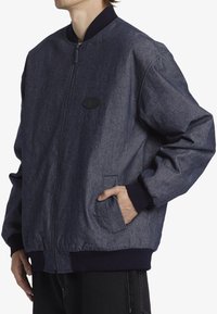 Mörkblå denim bomberjacka med en ribbad marinblå krage, frontdragkedja, sidofickor och en strukturerad tygfinish. Klassisk design.