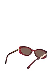 Punaiset muoviset aurinkolasit, joissa on ruskeat linssit, kissan silmä -muoto, kultaiset yksityiskohdat templeissä ja kiiltävä pinta.